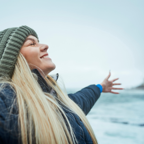 Woman stretching her arms out and smiling with her eyes closed.