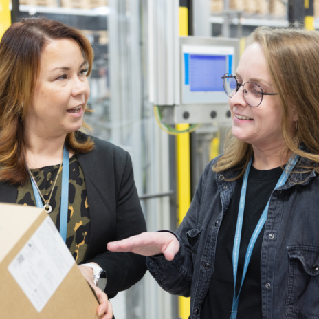 Two Serres employees smiling and discussing while pointing at a product package.