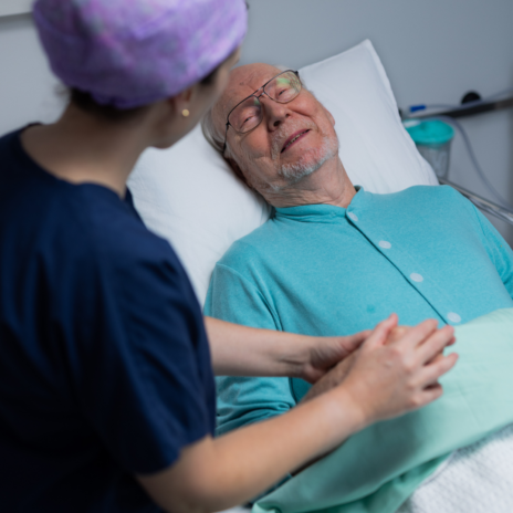 Nurse holding the hand of an older patient.